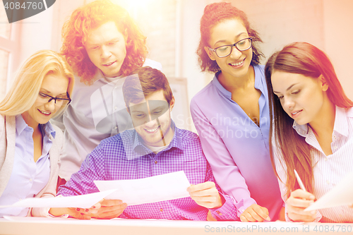 Image of smiling team with paper at office