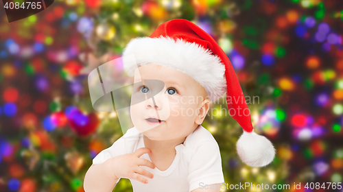 Image of baby boy in christmas santa hat over blue lights