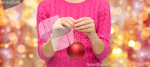 Image of close up of woman in sweater with christmas ball