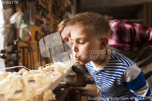 Image of father and little son with wood plank at workshop
