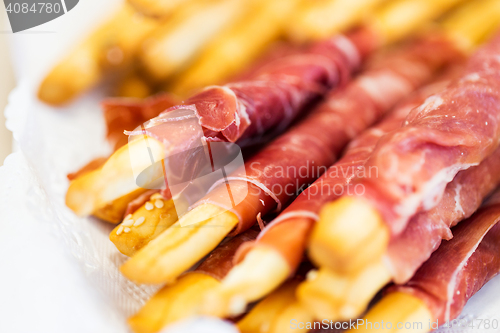 Image of close up of grissini bread sticks with prosciutto