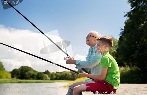 Image of grandfather and grandson fishing on river berth