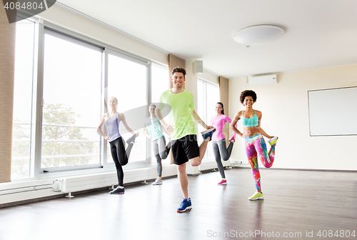 Image of group of smiling people exercising in gym