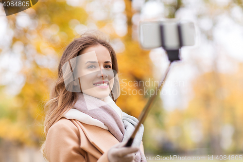 Image of woman taking selfie by smartphone in autumn park