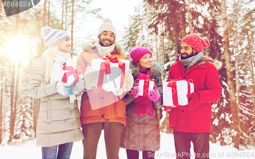 Image of happy friends and christmas gifts in winter forest