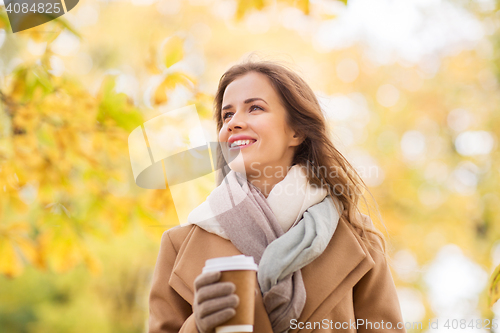 Image of happy young woman drinking coffee in autumn park