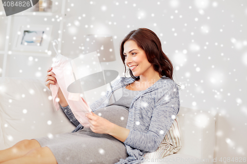 Image of happy woman holding baby girls bodysuit at home