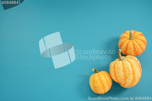 Image of Three yellow and orange Festival squash on blue wooden backgroun