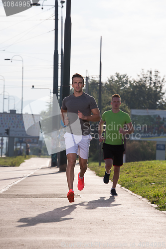 Image of Two young men jogging through the city