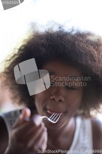 Image of a young African American woman eating pasta