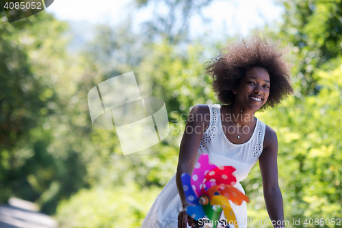 Image of pretty young african american woman riding a bike in forest