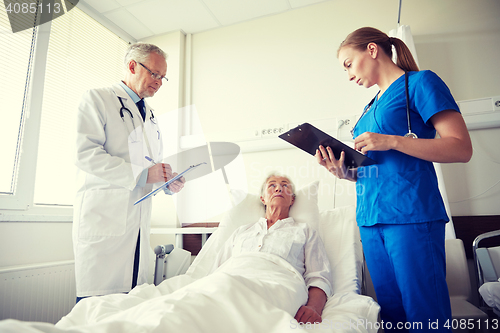 Image of doctor and nurse visiting senior woman at hospital