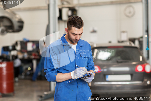 Image of auto mechanic man with clipboard at car workshop