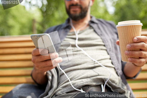Image of man with earphones and smartphone drinking coffee