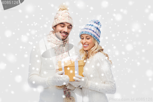 Image of smiling couple in winter clothes with gift box