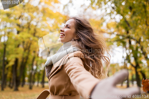 Image of beautiful happy young woman walking in autumn park