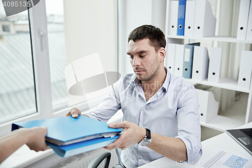 Image of businessman taking folder from secretary in office