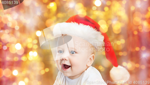 Image of baby boy in christmas santa hat over blue lights