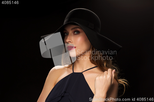 Image of beautiful woman in black hat over dark background
