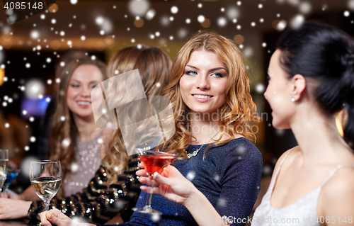 Image of happy women with drinks at night club over snow