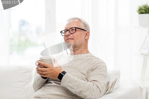 Image of happy senior man with cup of tea at home