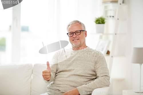 Image of smiling senior man showing thumbs up at home