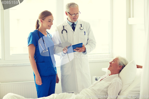 Image of doctor and nurse visiting senior woman at hospital