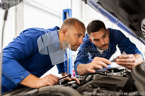 Image of mechanic men with wrench repairing car at workshop