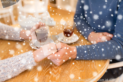 Image of close up of couple holding hands at restaurant