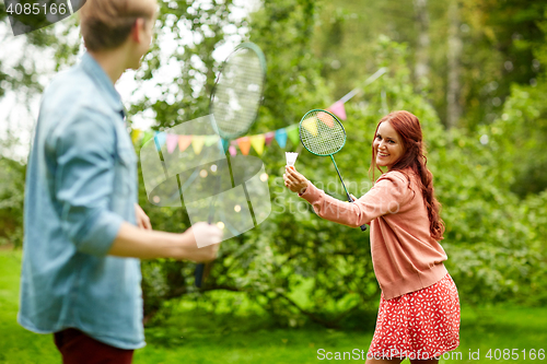 Image of happy friends playing badminton at summer garden