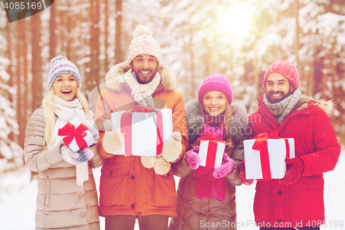 Image of happy friends with gift boxes in winter forest