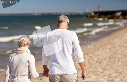 Image of senior couple walking along summer beach