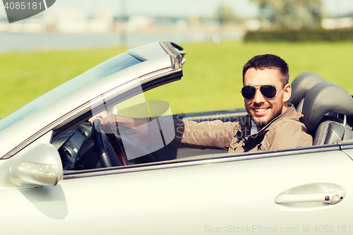 Image of happy man driving cabriolet car outdoors