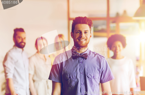 Image of happy young man over creative team in office