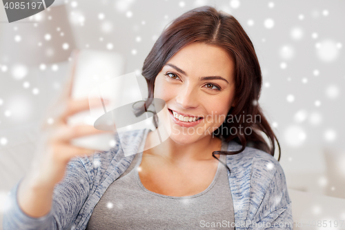 Image of happy woman taking selfie with smartphone at home