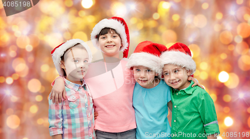 Image of happy little children in santa hats hugging