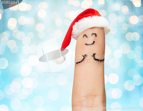 Image of close up of one finger in santa hat over lights