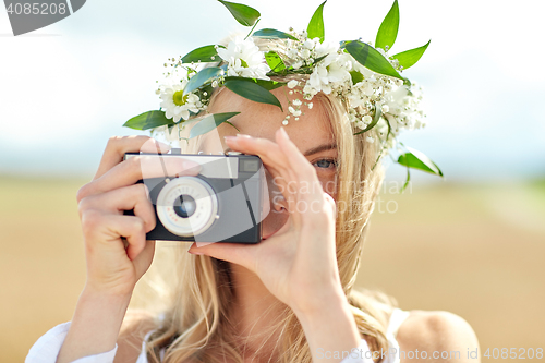 Image of happy woman with film camera in wreath of flowers