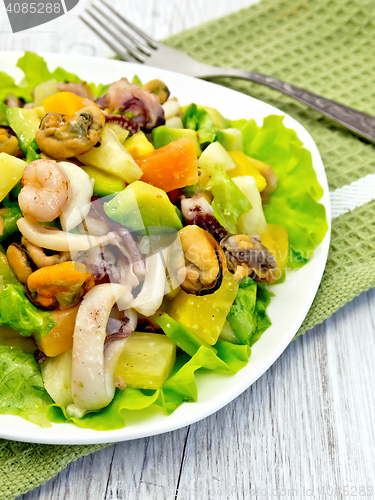 Image of Salad with seafood and avocado in plate on  light board