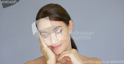 Image of Single young woman in brown hair with hand on face