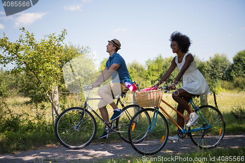 Image of Young multiethnic couple having a bike ride in nature