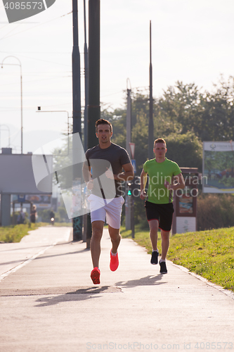 Image of Two young men jogging through the city