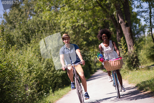 Image of Young multiethnic couple having a bike ride in nature