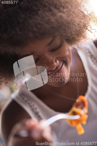 Image of a young African American woman eating pasta