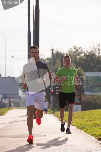 Image of Two young men jogging through the city