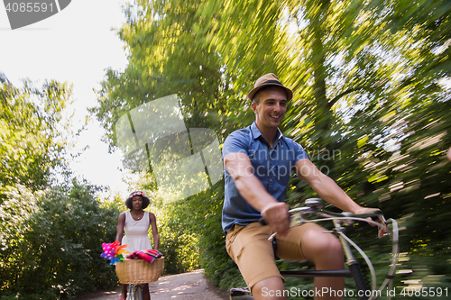 Image of Young multiethnic couple having a bike ride in nature
