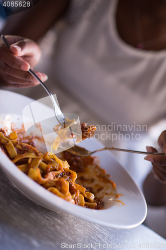 Image of a young African American woman eating pasta