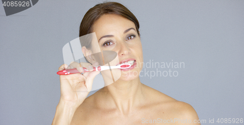 Image of Smiling pretty young woman brushing her teeth