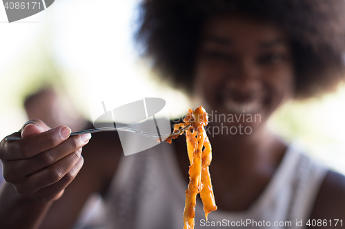 Image of a young African American woman eating pasta