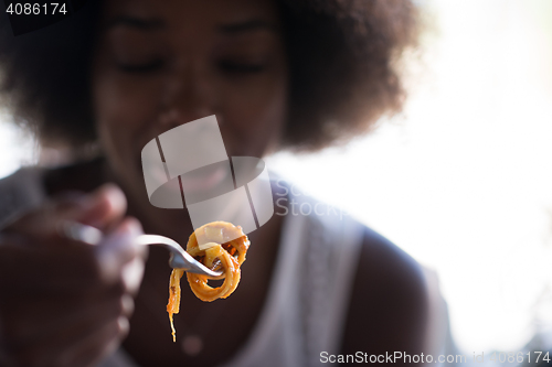 Image of a young African American woman eating pasta